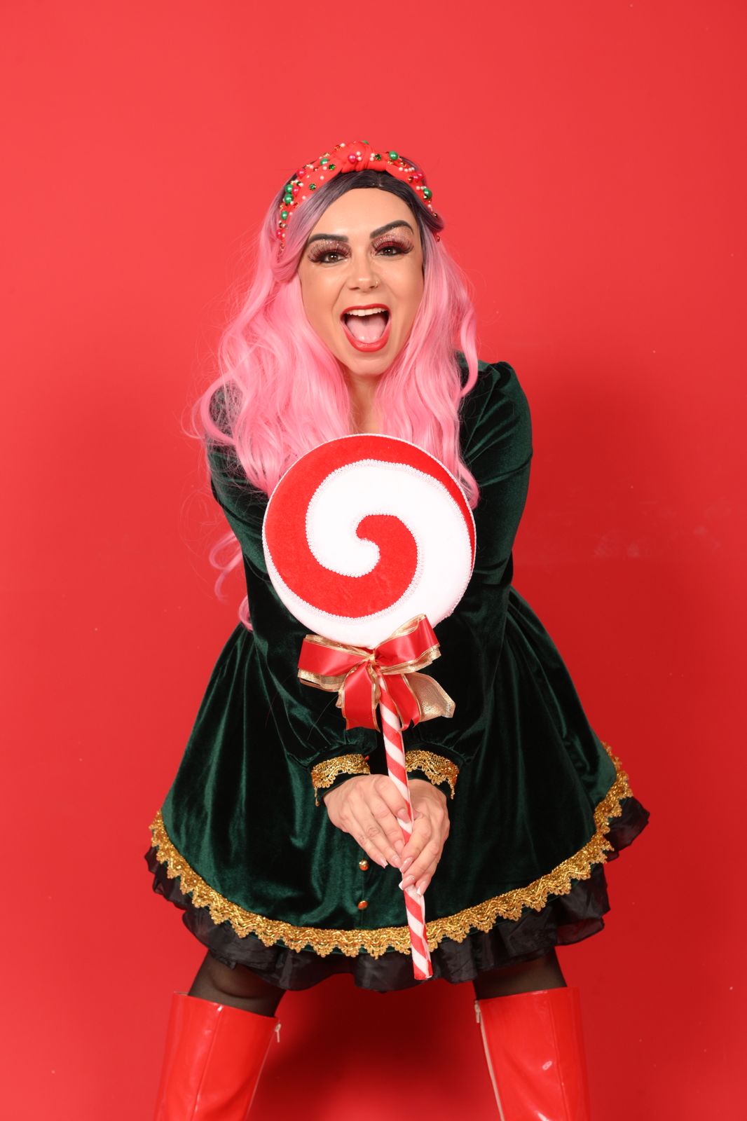 Tina Show com figurino de Natal segurando um pirulito gigante