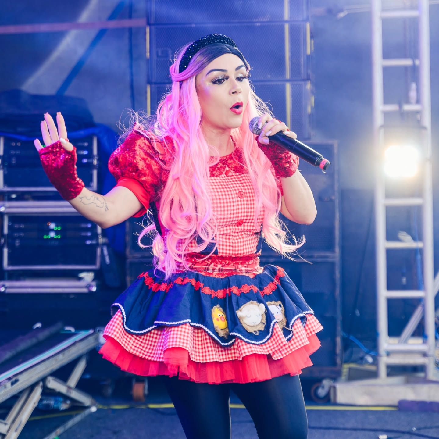 Tina Show cantando no palco com luzes azuis