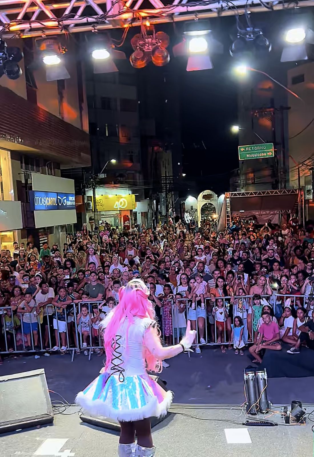 Tina de costas para uma multidão em show na rua